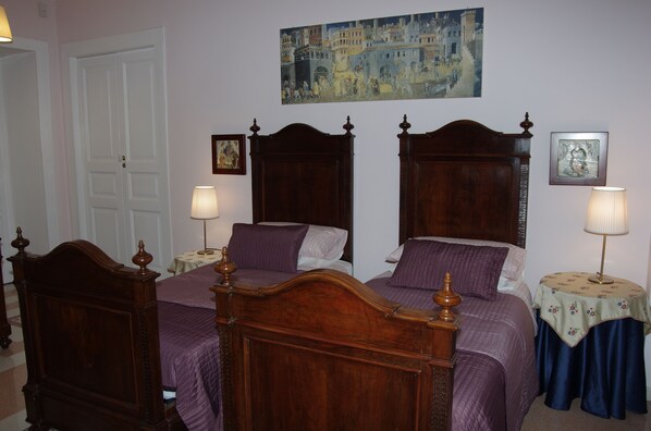 A bedroom with two wooden beds, a painting on the wall, and a door. - La magnolia B&B (Baronissi)