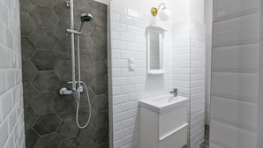 Une salle de bain moderne équipée d’une douche, d’un lavabo et d’un miroir.