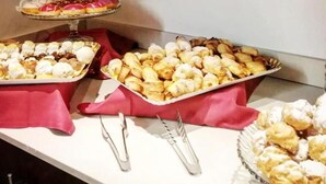 Un tavolo da buffet con diverse paste e dolci, tra cui éclair e macarons, ricoperto da tovaglie rosse.