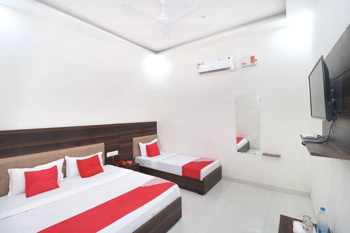 Ein Hotelzimmer mit zwei Betten, einem Deckenventilator, einer Klimaanlage, einem Fernseher und einem Spiegel.