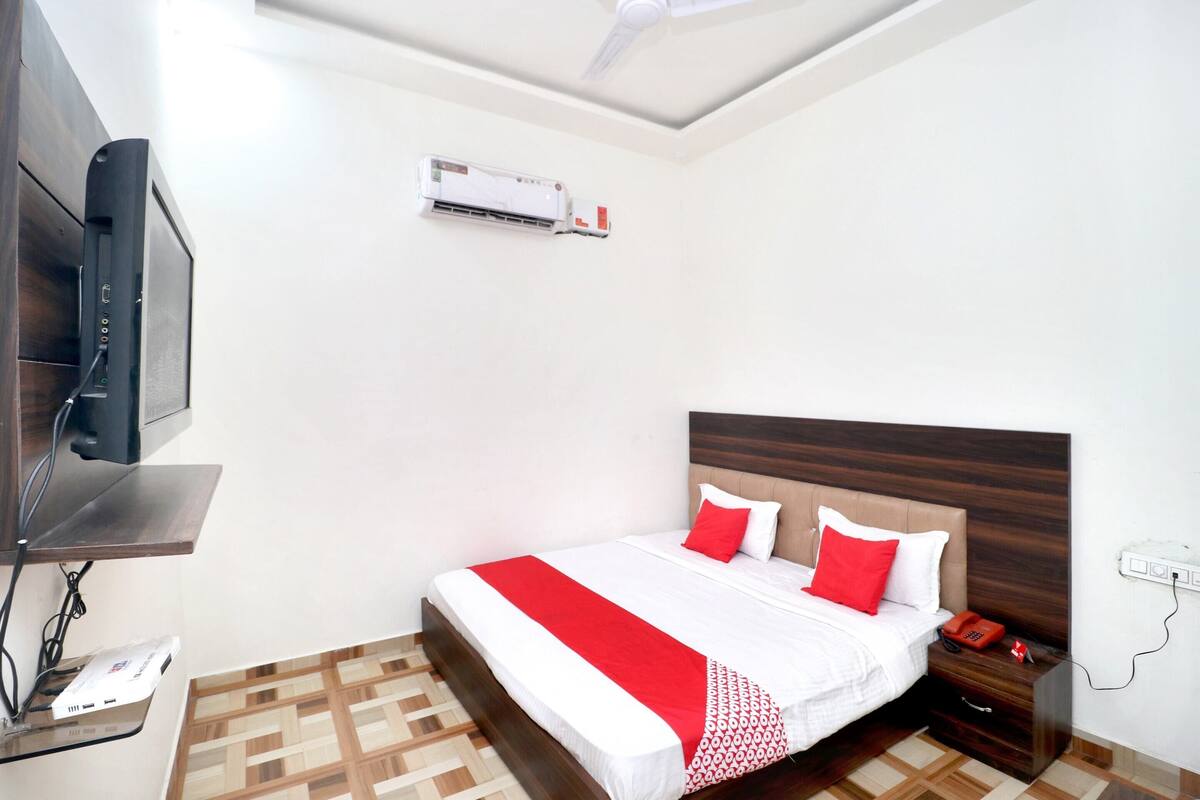 Ein ordentlich eingerichtetes Hotelzimmer mit Bett, Nachttisch und einem an der Wand befestigten Fernseher.