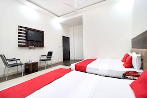 A hotel room with two beds, a TV mounted on the wall, a desk with a chair, and a door leading to another room. - OYO 16379 Hotel LivInn Hub (Amritsar)