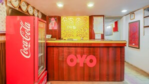 A reception desk with a Coca-Cola refrigerator, a clock, and a decorative panel. - OYO Flagship 12273 Hotel Indraprastha (Chhatrapati Sambhajinagar)