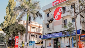 A building with a prominent OYO Hotel sign, a bank with a blue sign, and several parked scooters. - OYO Flagship 12273 Hotel Indraprastha (Chhatrapati Sambhajinagar)