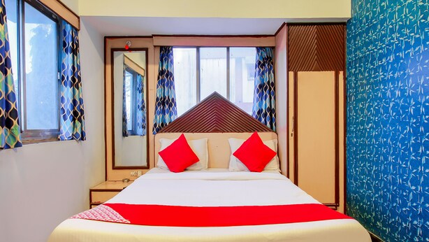 A hotel room with a bed, a nightstand, a mirror, and a wardrobe. - OYO Flagship 12273 Hotel Indraprastha (Chhatrapati Sambhajinagar)