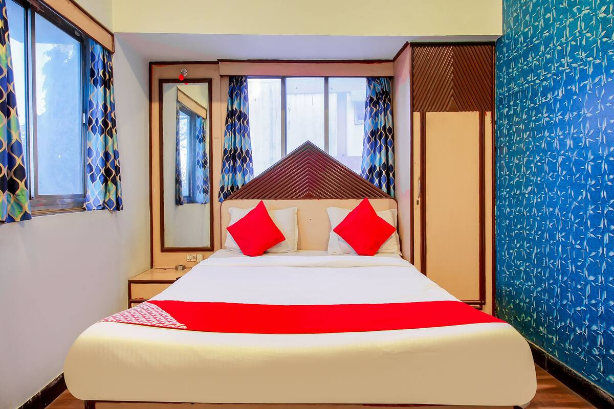 A hotel room with a bed, a nightstand, a mirror, and a wardrobe.