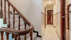 A hotel hallway with a wooden staircase and a door with a number. - OYO Flagship 12273 Hotel Indraprastha (Chhatrapati Sambhajinagar)
