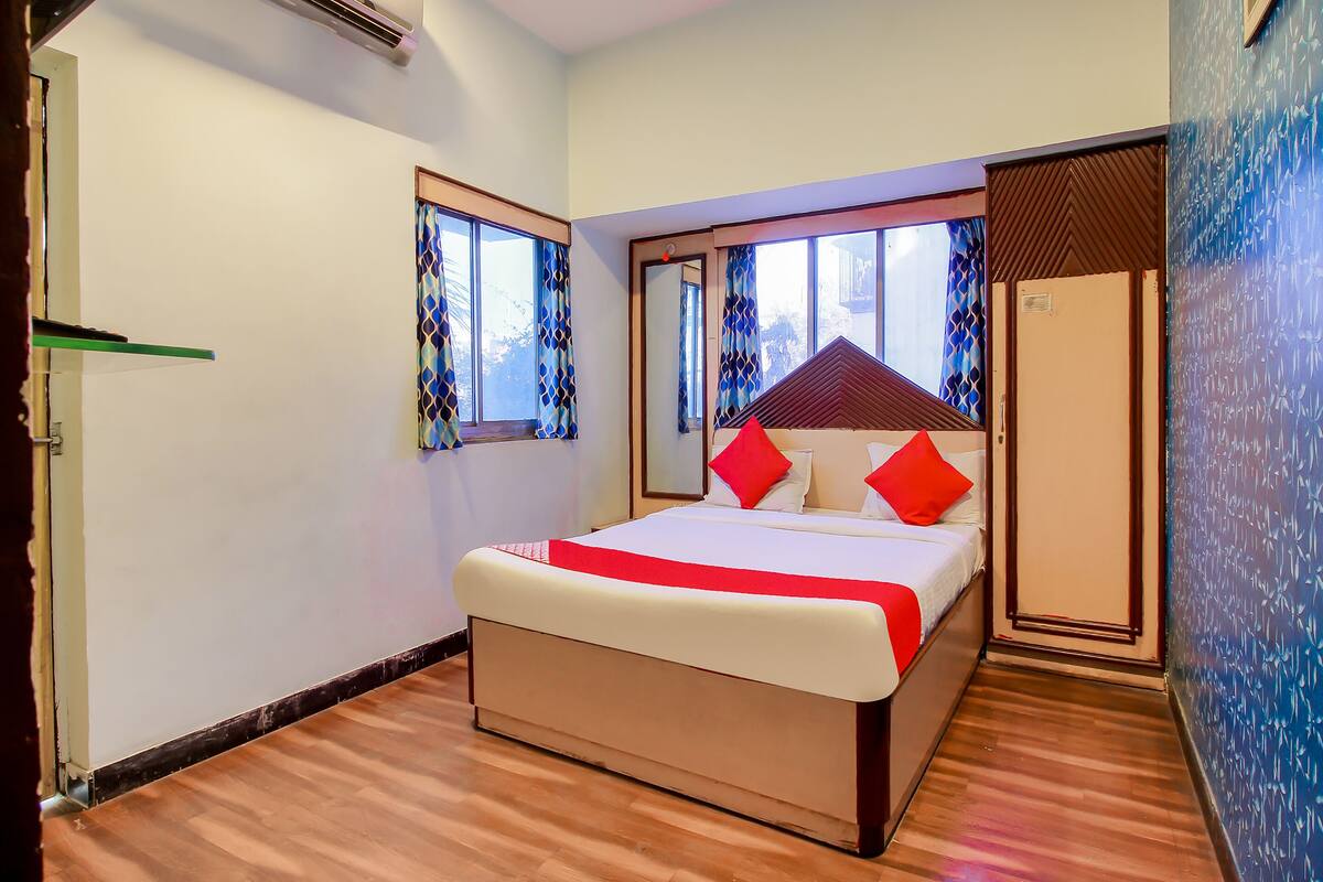 A bedroom with a bed, a wardrobe, and a window with patterned curtains.