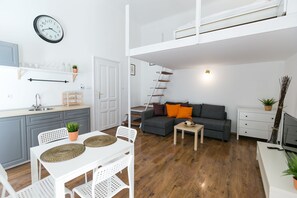 A modern apartment with a kitchen, dining area, and living room. It features a loft bedroom with a staircase, a white sofa, and a TV. - Sparkling Ernesto IV (Budapest)