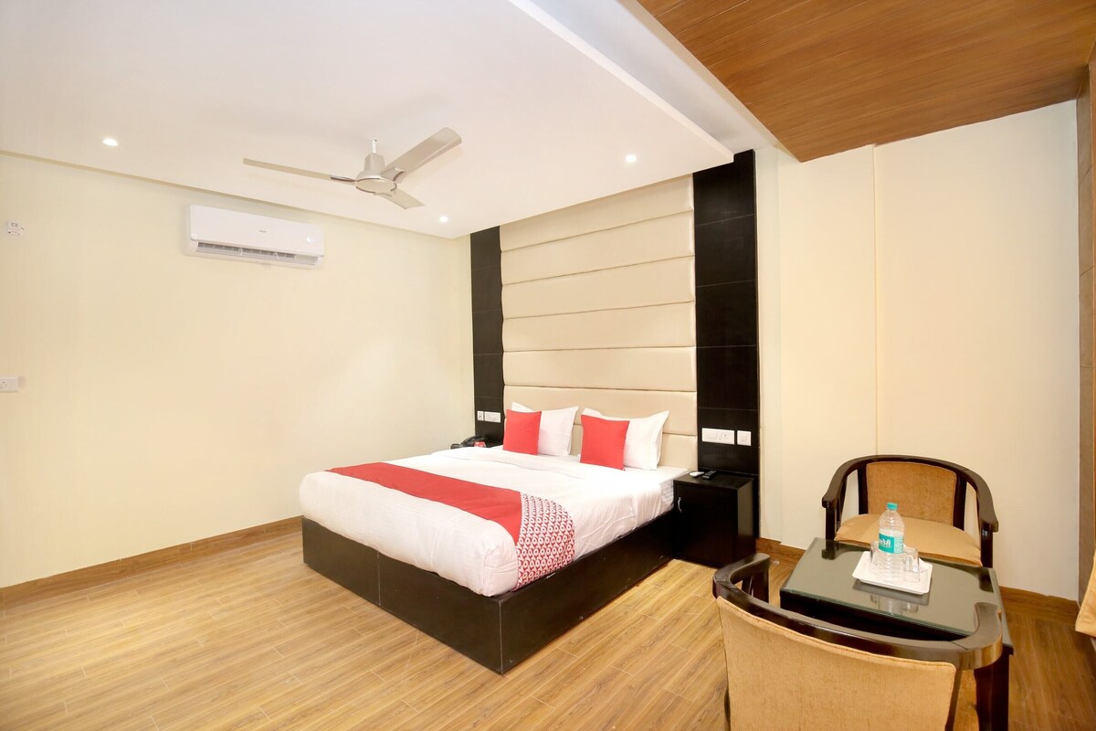 A hotel room with a bed, bedside table, chair, and a ceiling fan.