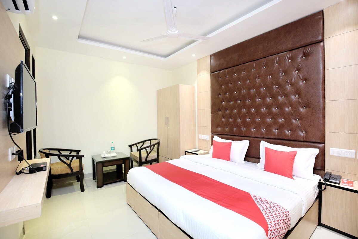 A hotel room with a large bed, a TV mounted on the wall, a desk, and a chair.