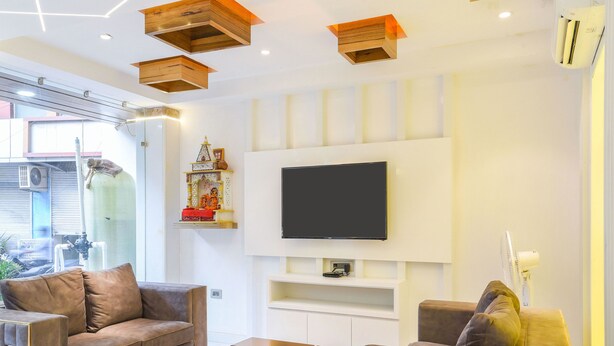 Un salon moderne comprenant deux canapés, une table basse, un téléviseur à écran plat et une étagère décorative.