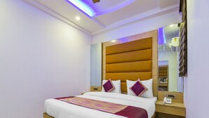 Une chambre d’hôtel avec un grand lit, une tête de lit en bois, une table de chevet avec un téléphone et un miroir.