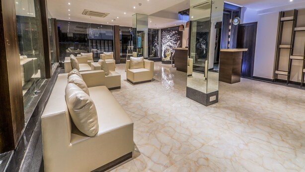 A modern lobby with a marble floor, leather sofas, and a reception desk. - OYO 16719 Airport Guest House (Guwahati)