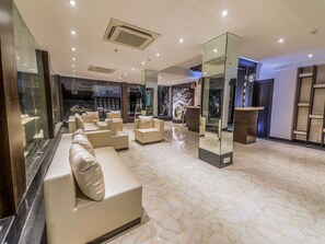 A modern lobby with a marble floor, leather sofas, and a reception desk. - OYO 16719 Airport Guest House (Guwahati)