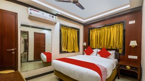 A hotel room with a bed, a nightstand, a mirror, a ceiling fan, and an air conditioning unit. - OYO 16719 Airport Guest House (Guwahati)