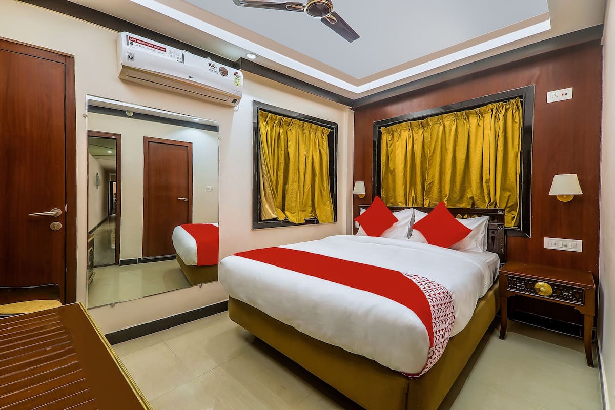 Une chambre d’hôtel équipée d’un lit, d’une table de chevet, d’un miroir, d’un ventilateur de plafond et d’un appareil de climatisation.