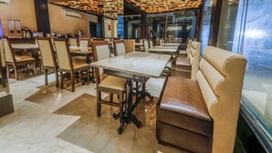 A restaurant interior with marble flooring, wooden tables and chairs, and a ceiling with circular light fixtures. - OYO 16719 Airport Guest House (Guwahati)