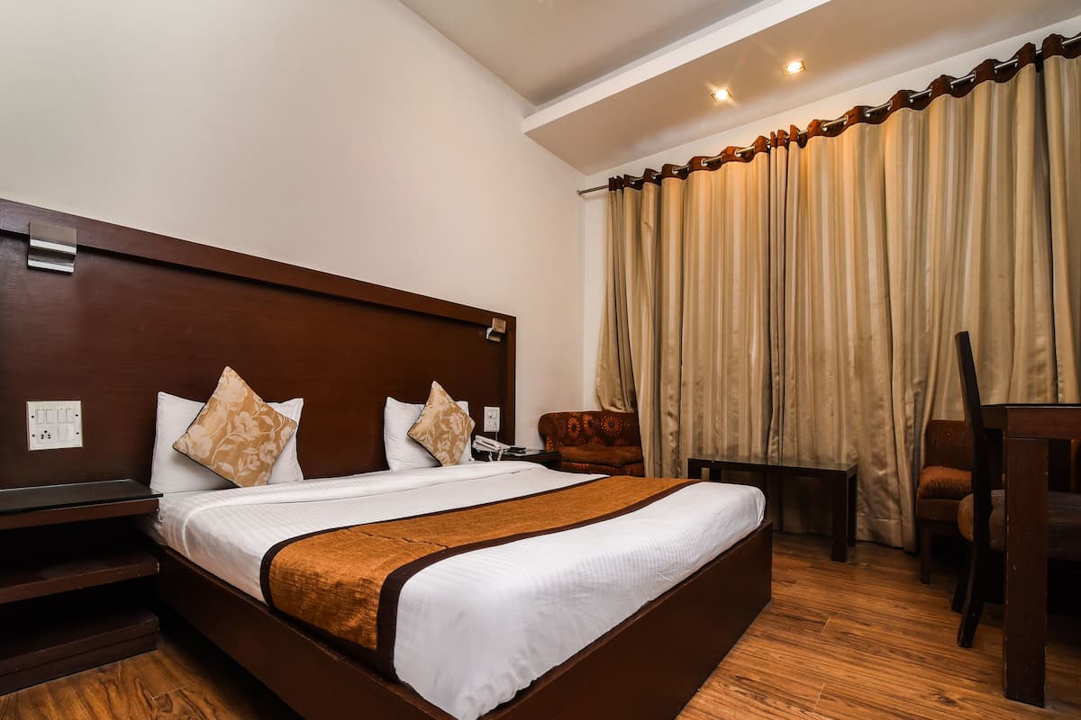 Ein Hotelzimmer mit einem großen Bett, einem Holzkopfende, einem Schreibtisch und einem Stuhl.