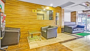 Un hall d’entrée avec un mur en bois, deux canapés en cuir, une table basse en verre et un comptoir d’accueil.