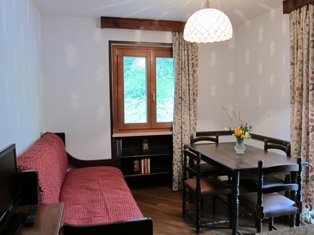 Une pièce confortable avec un lit, une télévision, une table à manger avec des chaises et une fenêtre avec des rideaux.