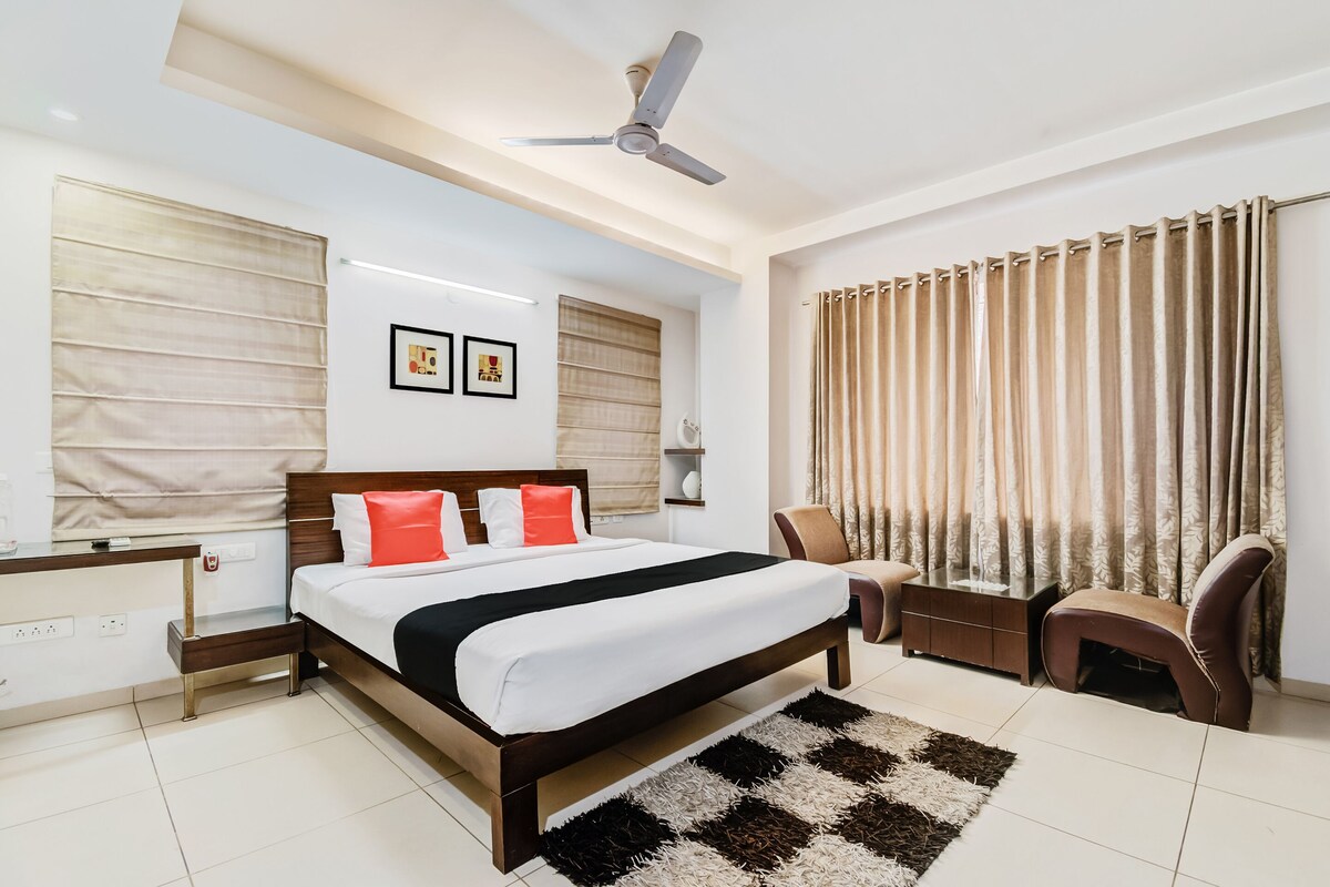 A modern bedroom with a bed, bedside tables, a ceiling fan, and a large window with curtains.