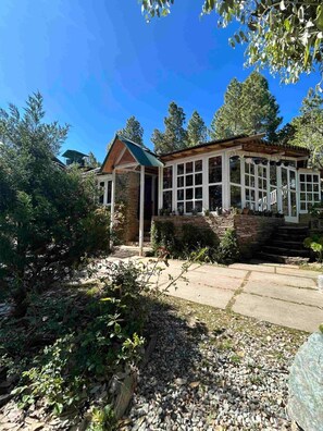A house with a stone exterior, a wooden porch, and a large windowed front area. - Frozen Woods Resorts (Kosiyakutoli)