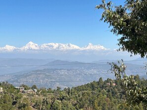A mountainous landscape with snow-capped peaks and a foreground of trees and buildings. - Frozen Woods Resorts (Kosiyakutoli)