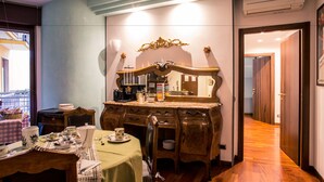 A dining area with a wooden table set for two, a vintage mirror above the table, and a view of a balcony through an open door. - 10 Minutes B&B (Verona)