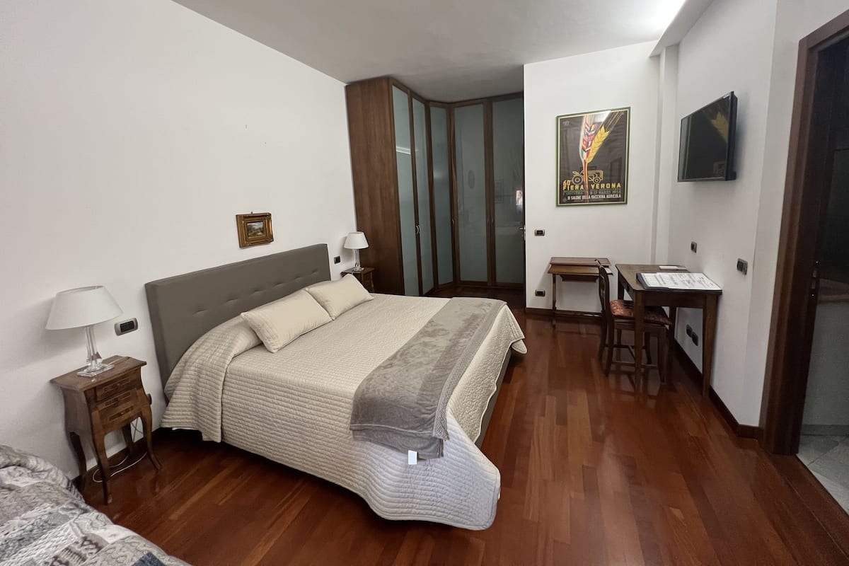 A bedroom with a bed, bedside tables, a desk, and a chair.