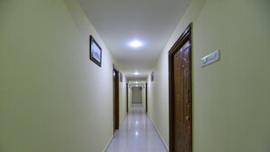 A long, narrow hallway with a tiled floor and wooden doors on either side. - OYO 12765 Hotel Golden Rooms (Tirupati)