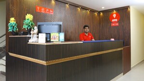 A reception desk with a monitor, a sign indicating Wi-Fi availability, and a logo for OYO. - OYO 12765 Hotel Golden Rooms (Tirupati)