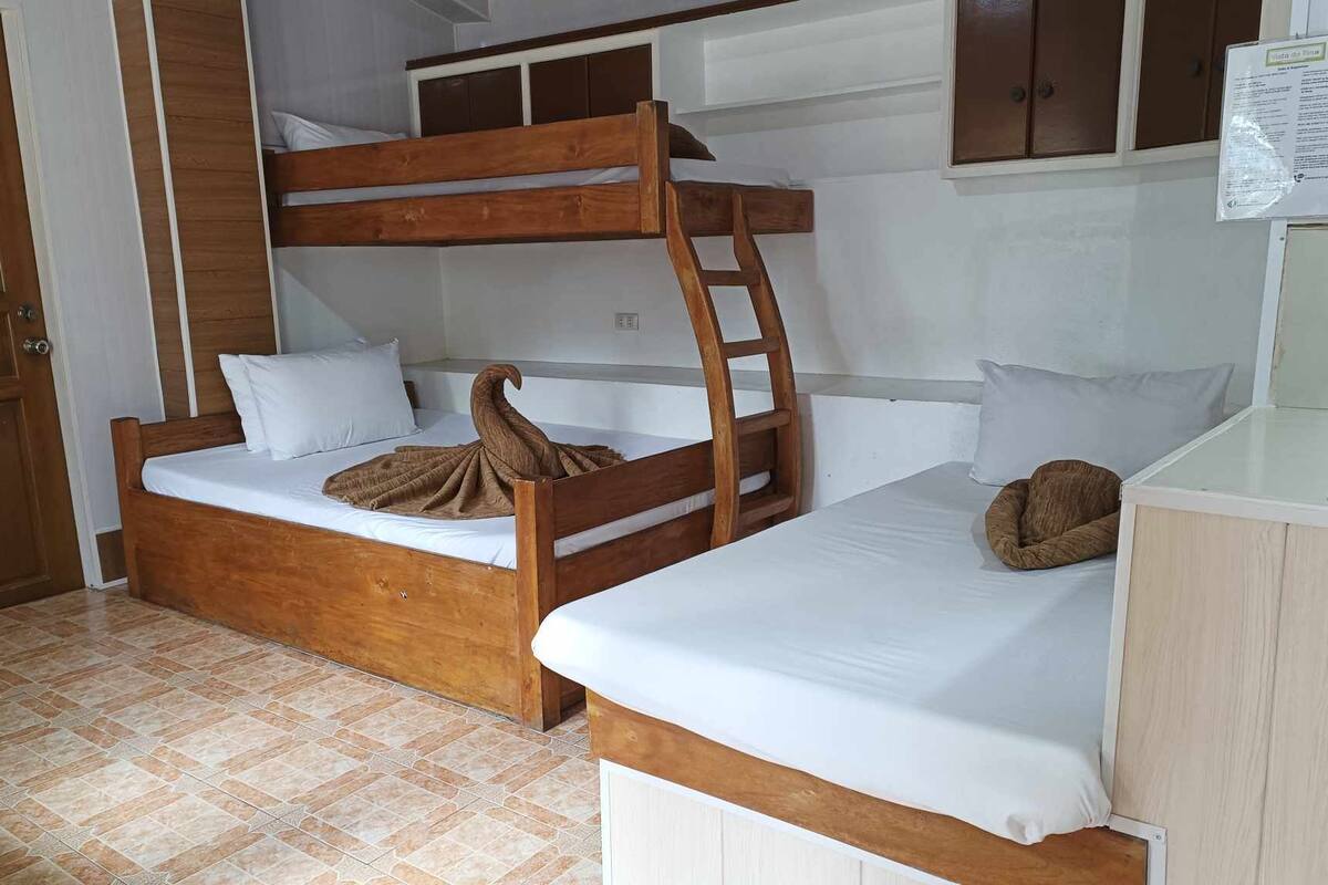 Een slaapkamer met een stapelbed, een houten ladder, wit beddengoed en een klein bureau.