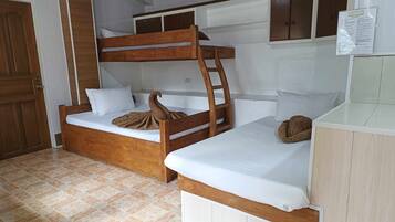 A bunk bed room with a wooden ladder, white bedding, and a small desk area.
