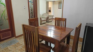A dining area with a wooden table and chairs, a patterned door, and a kitchen in the background. - Vista de Pino (Baguio)