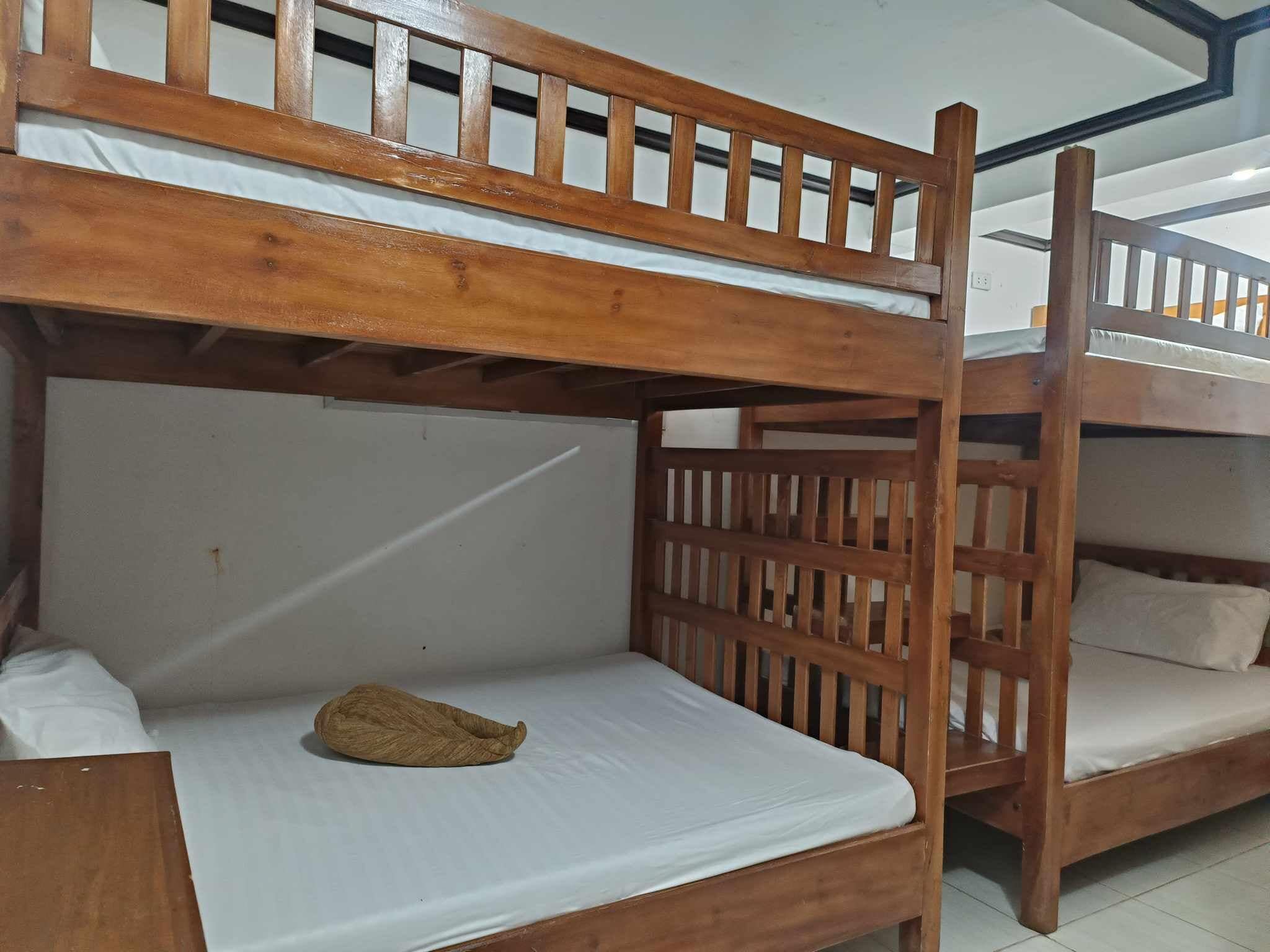 A bunk bed room with wooden railings and white bedding.