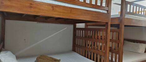 A bunk bed room with wooden railings and white bedding.