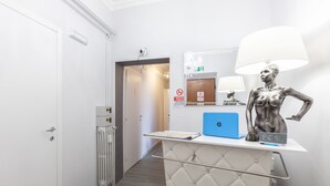 A hotel room with a minibar, a lamp, a laptop, and a statue on the counter. - Heart of San Lorenzo (Rome)