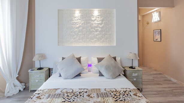 A bedroom with a large bed, two bedside tables, a wall-mounted artwork, and a framed picture on the wall. - Heart of San Lorenzo (Rome)