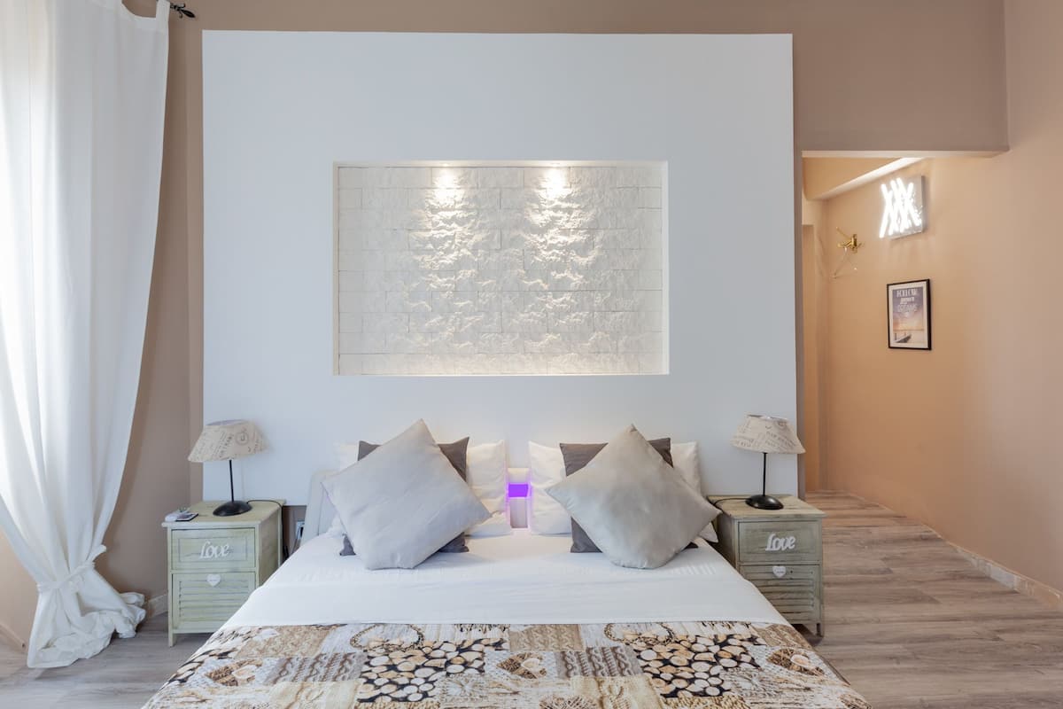 A bedroom with a large bed, two bedside tables, a wall-mounted artwork, and a framed picture on the wall.