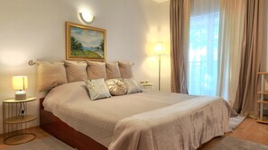 A neatly arranged bedroom with a large bed, two bedside tables, a wall-mounted lamp, and a painting above the bed. - Avalena Rooms (Zadar)