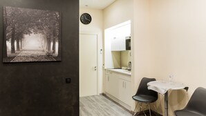 Una cocina moderna con encimera blanca, un reloj y un comedor con dos sillas y una mesa.