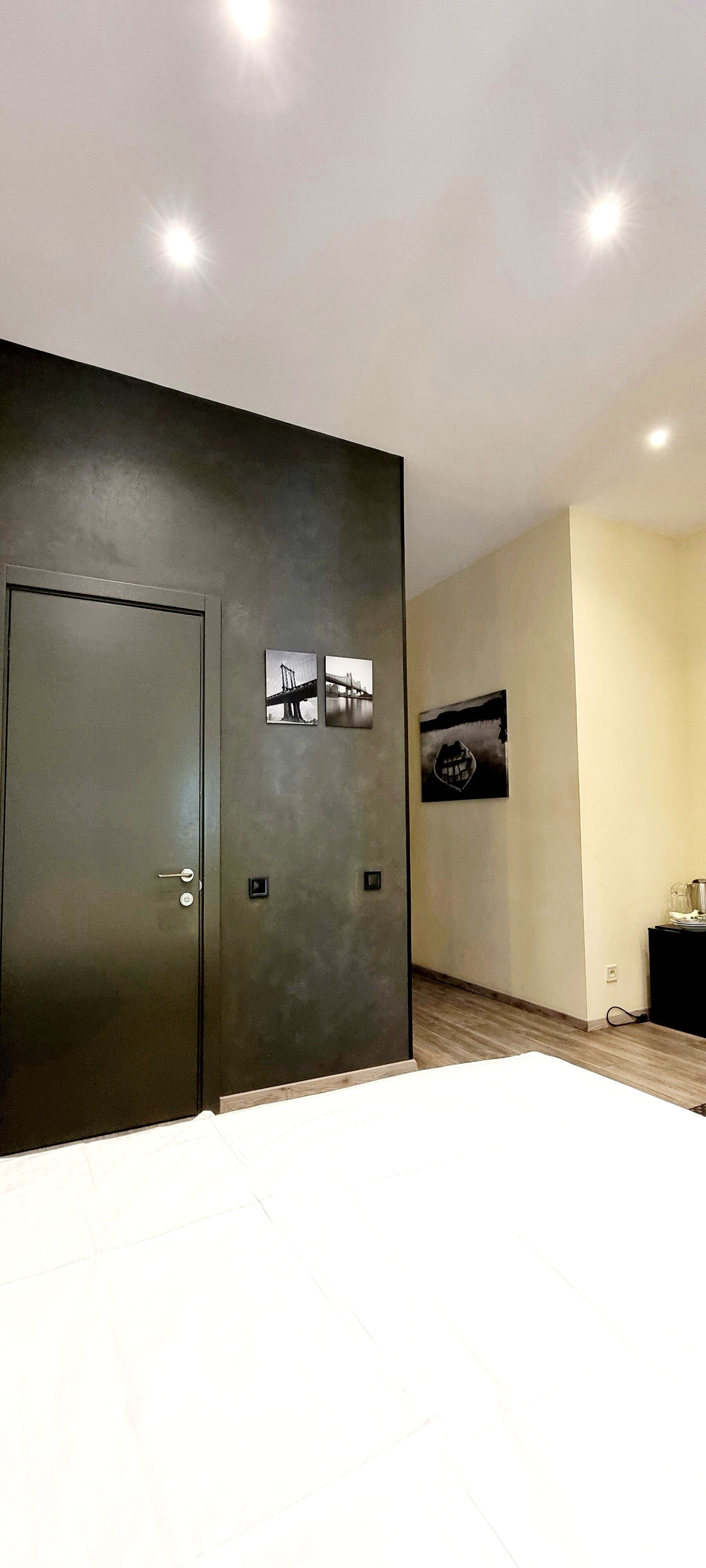 A hotel room with a large bed, a dark-colored wardrobe, and two framed pictures on the wall.
