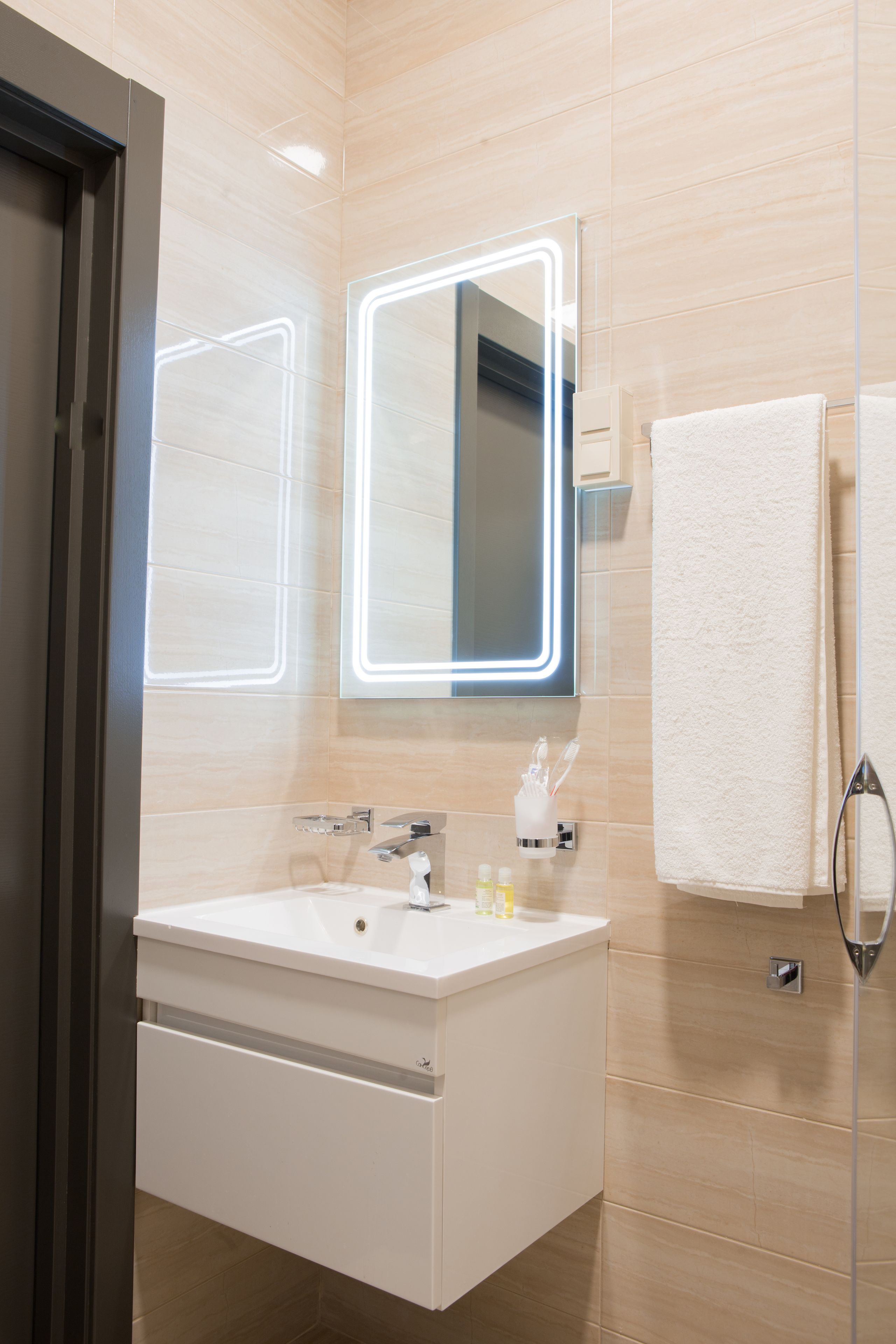 A modern bathroom with a white sink, two mirrors, and a towel rack.