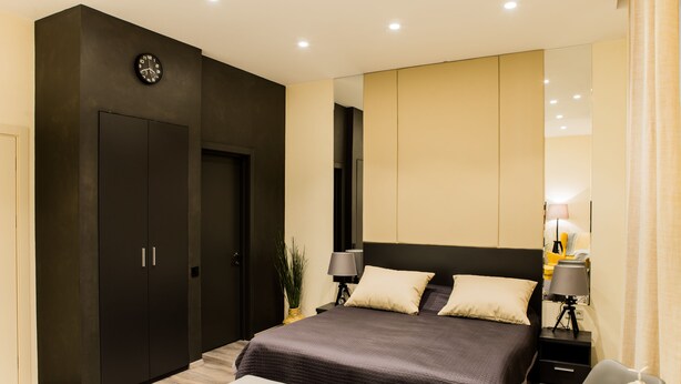 Un dormitorio moderno con una cama grande, un armario, un escritorio y una silla.