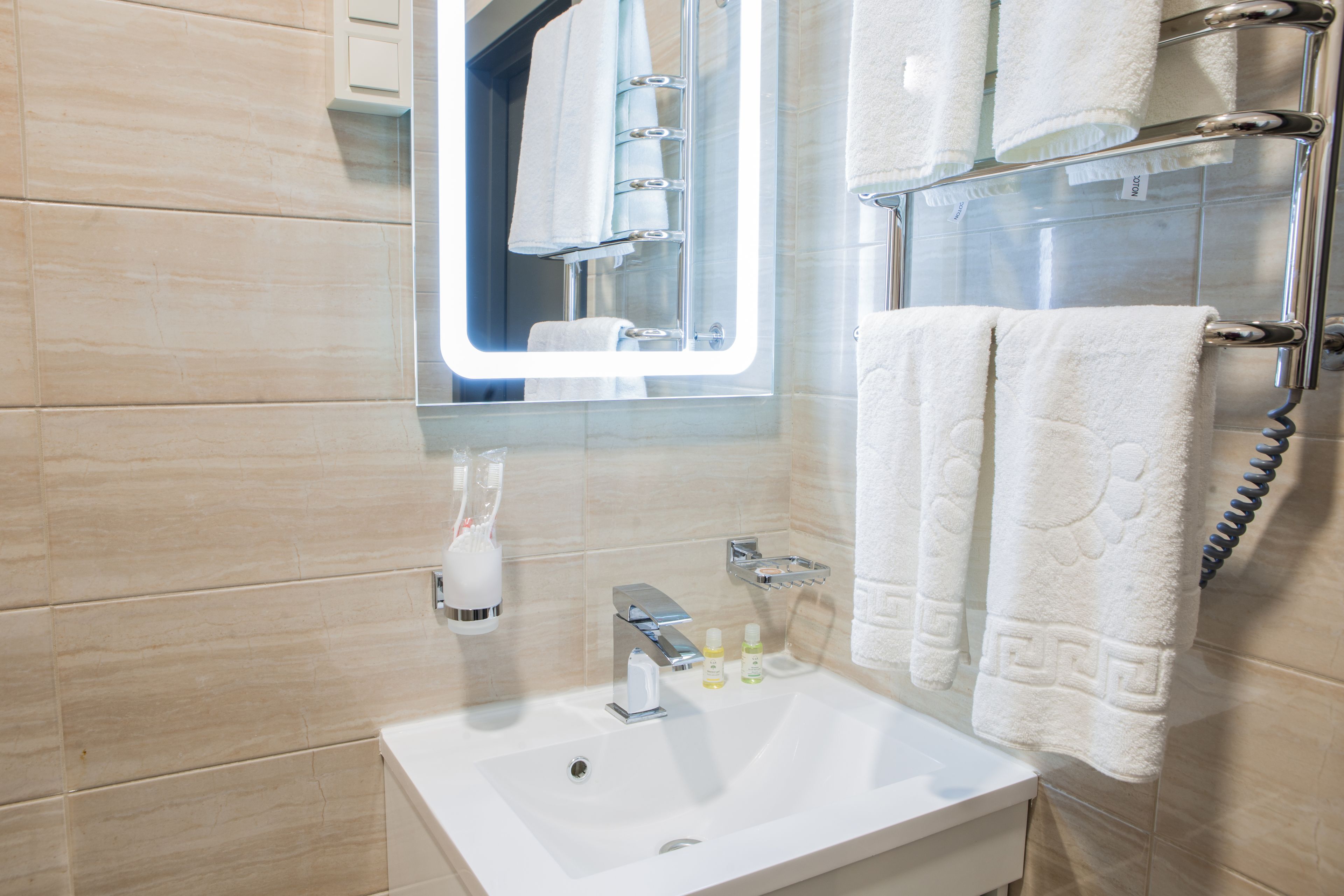A bathroom with a white sink, a mirror, a towel rack, and a glass shower enclosure.