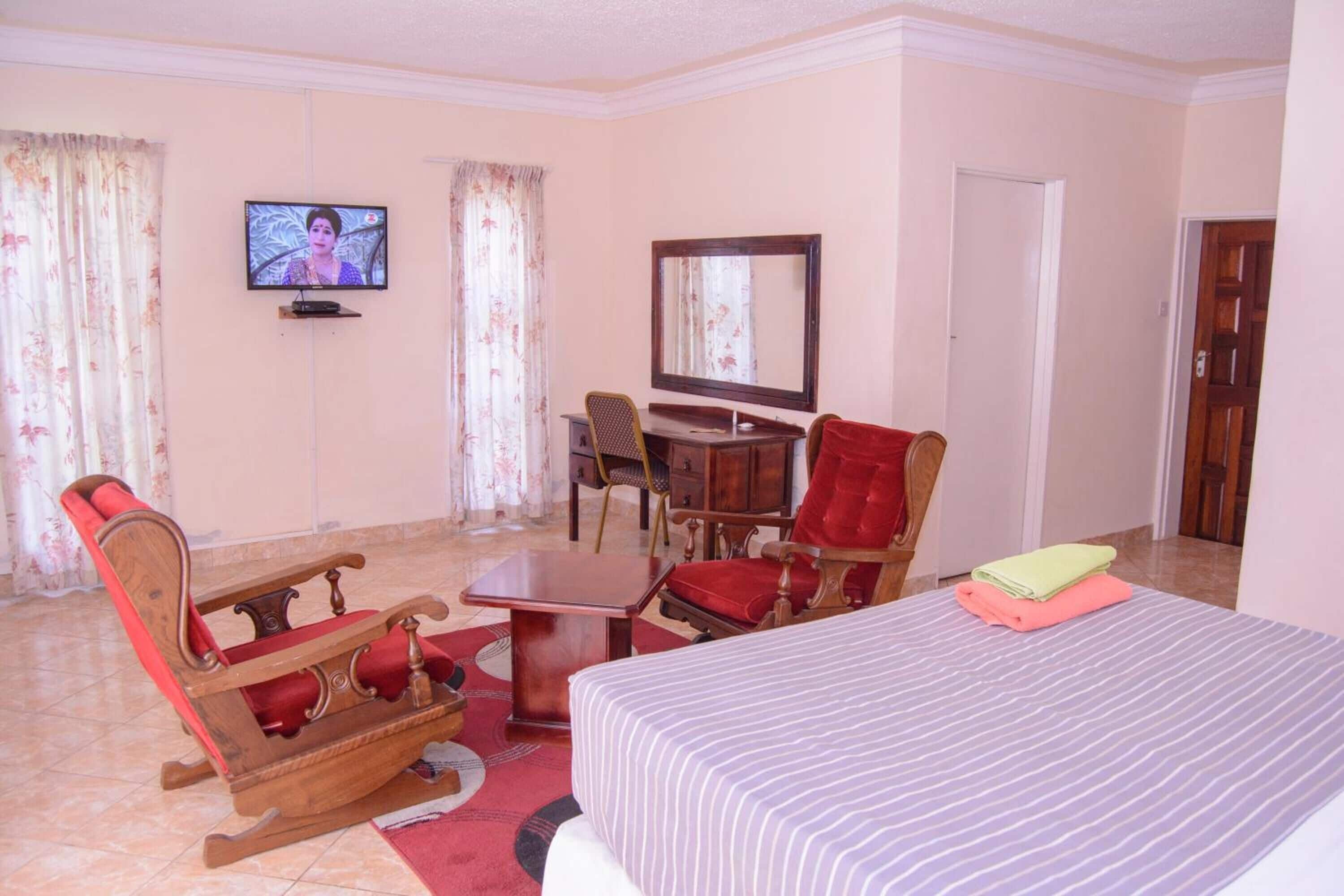 A hotel room with a bed, a television, a desk, a chair, and a mirror.