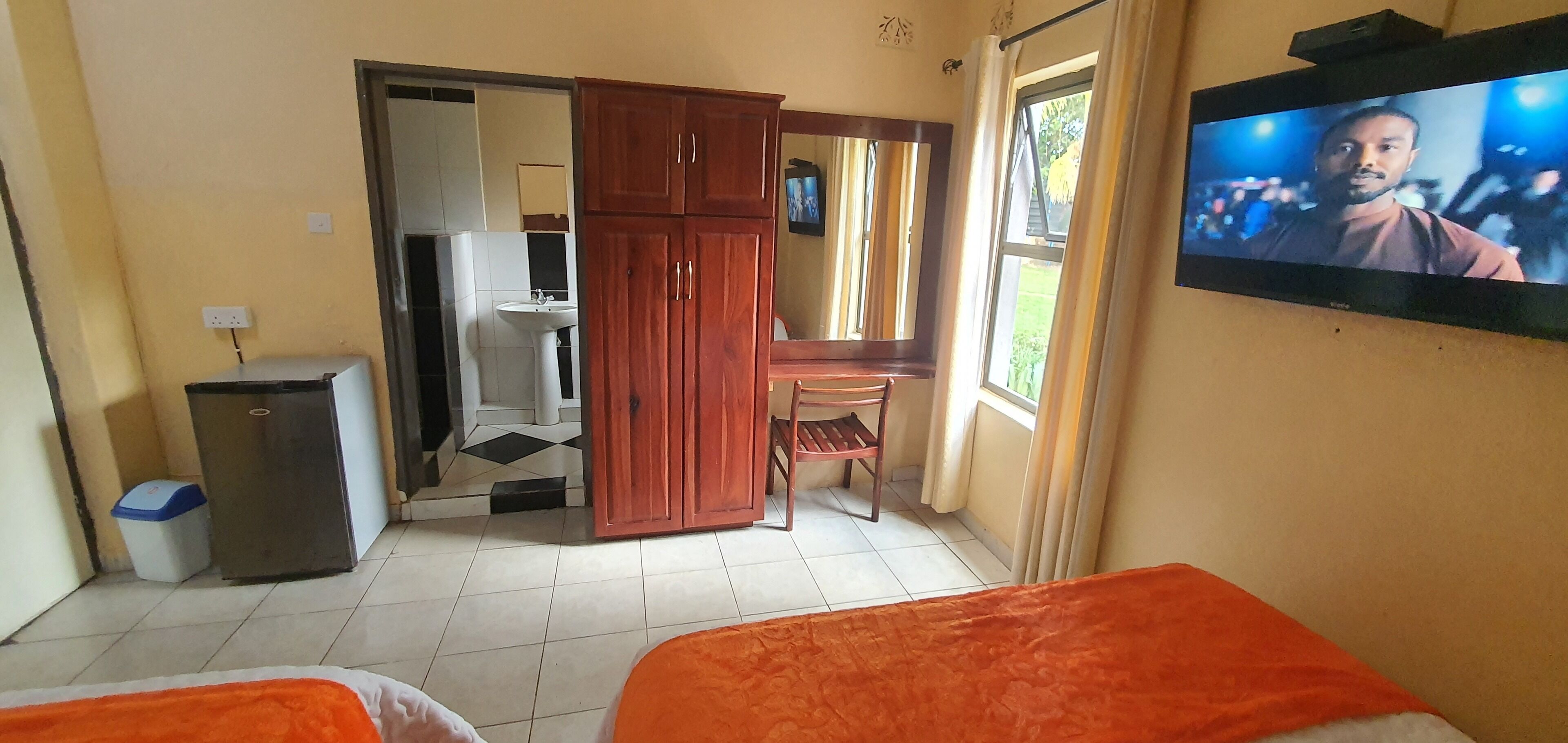Een hotelkamer met twee bedden, een bureau, een televisie en een kledingkast.