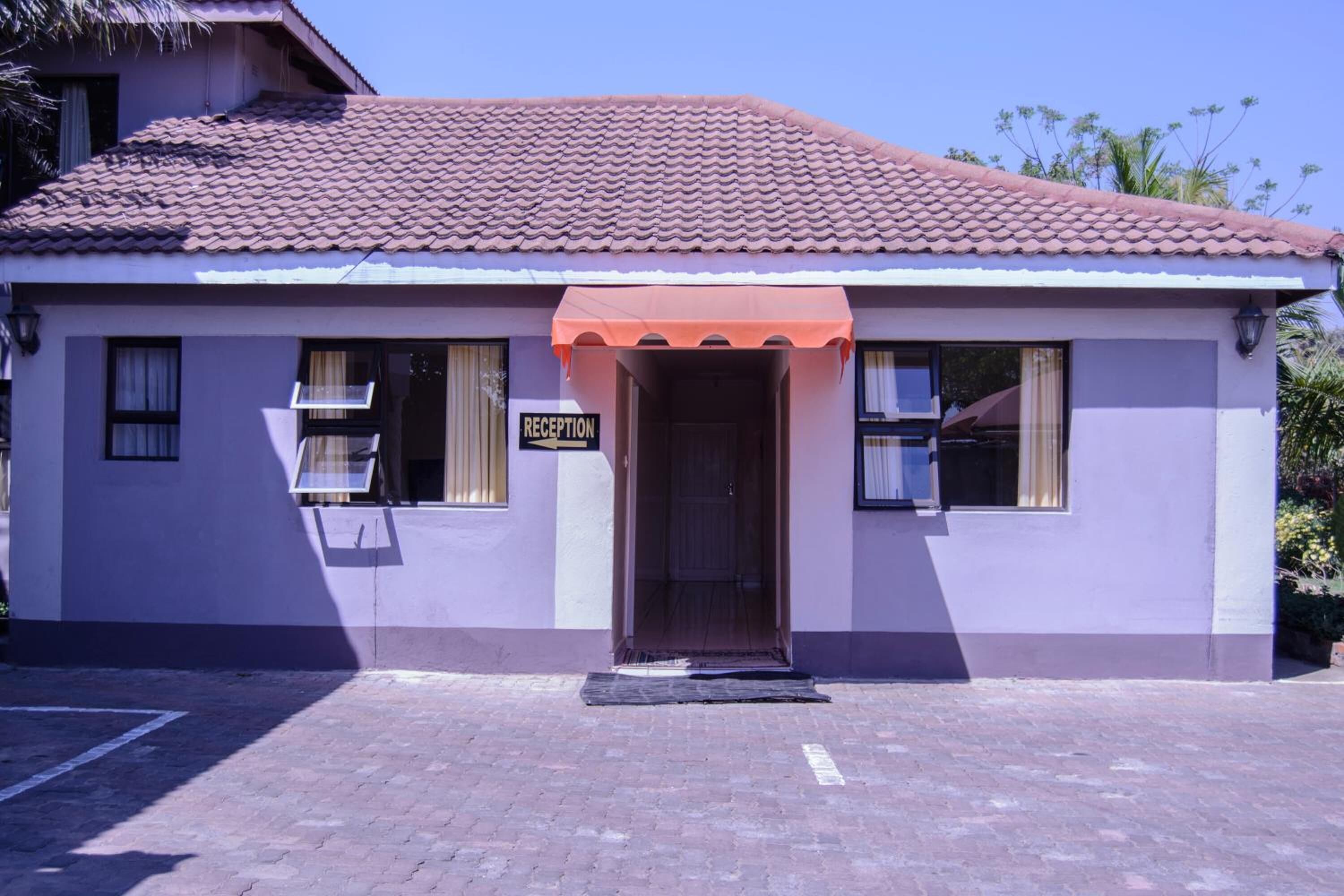 A building with a reception area, a tiled roof, and a paved entrance.