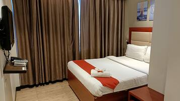 A hotel room with a bed, a nightstand, a TV, and curtains.